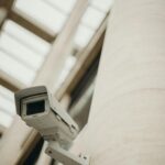 Close-up of a security camera on a building wall, showcasing surveillance technology.